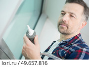 man with silicone sealant and caulking gun in hands. Стоковое фото, агентство Ingram Publishing / Фотобанк Лори