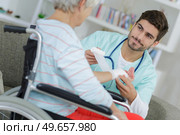 Young male nurse bandaging elderly woman's wrist. Стоковое фото, агентство Ingram Publishing / Фотобанк Лори