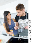 Couple cooking meal, lady holding salt mill. Стоковое фото, агентство Ingram Publishing / Фотобанк Лори