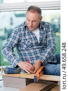 craftsman measuring a plank of wood with a spirit level. Стоковое фото, агентство Ingram Publishing / Фотобанк Лори