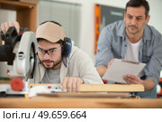 male apprentice using circular saw under supervision. Стоковое фото, агентство Ingram Publishing / Фотобанк Лори