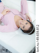 Lady layed on couch listening to headphones. Стоковое фото, агентство Ingram Publishing / Фотобанк Лори