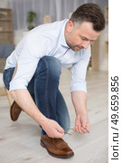 man tying red shoelaces casual shoes on floor. Стоковое фото, агентство Ingram Publishing / Фотобанк Лори