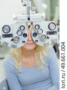 Woman behind optician's eye testing equipment. Стоковое фото, агентство Ingram Publishing / Фотобанк Лори