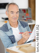 senior man assembling wooden furniture. Стоковое фото, агентство Ingram Publishing / Фотобанк Лори