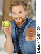 smiling man holding a donut and an apple. Стоковое фото, агентство Ingram Publishing / Фотобанк Лори