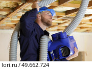 a plumber checking ceiling pipes. Стоковое фото, агентство Ingram Publishing / Фотобанк Лори