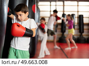 Teen boy in boxing gloves hits punching bag in gym. Стоковое фото, фотограф Яков Филимонов / Фотобанк Лори