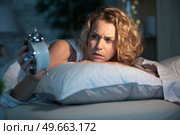 sleepless woman lying in bed looking at her clock. Стоковое фото, агентство Ingram Publishing / Фотобанк Лори