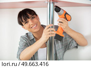 woman working on a new kitchen installation using cordless drill. Стоковое фото, агентство Ingram Publishing / Фотобанк Лори
