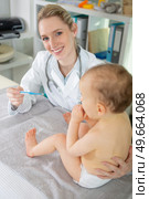 female paediatrician with baby holding a thermometer. Стоковое фото, агентство Ingram Publishing / Фотобанк Лори