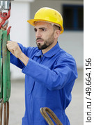 industrial operator attaching cords to hook. Стоковое фото, агентство Ingram Publishing / Фотобанк Лори