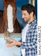 cowboy feeding his horse out of hand. Стоковое фото, агентство Ingram Publishing / Фотобанк Лори