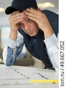 stressed builder worrying over blueprints. Стоковое фото, агентство Ingram Publishing / Фотобанк Лори