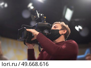 masked cameraman is filming a television show in the studio. TV. Стоковое фото, агентство Ingram Publishing / Фотобанк Лори