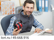 man holding earmuffs in the office. Стоковое фото, агентство Ingram Publishing / Фотобанк Лори