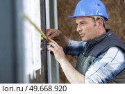 man measuring window prior to installation of roller shutter. Стоковое фото, агентство Ingram Publishing / Фотобанк Лори