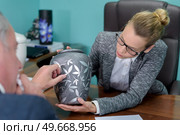 female funeral director showing urn to bereaved man. Стоковое фото, агентство Ingram Publishing / Фотобанк Лори