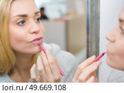 woman applying lip colour with pencil. Стоковое фото, агентство Ingram Publishing / Фотобанк Лори