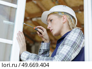 female builder making adjustment to window with screwdriver. Стоковое фото, агентство Ingram Publishing / Фотобанк Лори