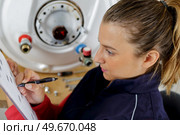 a female plumber checking boiler. Стоковое фото, агентство Ingram Publishing / Фотобанк Лори