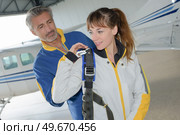 Man helping female parachutist put backpack on. Стоковое фото, агентство Ingram Publishing / Фотобанк Лори