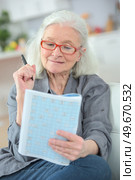 Elderly lady puzzling over a magazine quiz. Стоковое фото, агентство Ingram Publishing / Фотобанк Лори
