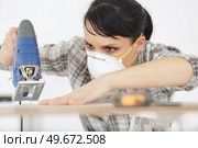 serious woman with mask cutting wood. Стоковое фото, агентство Ingram Publishing / Фотобанк Лори