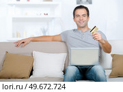 man with laptop on his lap holding card. Стоковое фото, агентство Ingram Publishing / Фотобанк Лори