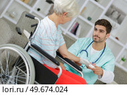 Young carer smiling pitifully at senior woman. Стоковое фото, агентство Ingram Publishing / Фотобанк Лори