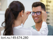 female optician fitting male clients eyeglasses. Стоковое фото, агентство Ingram Publishing / Фотобанк Лори