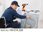 disabled repairman trying to fix a washing machine. Стоковое фото, агентство Ingram Publishing / Фотобанк Лори