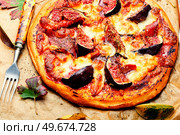 Meat pizza with figs. Flatbread with figs served on parchment paper. Classic pizza with prosciutto and fruit. Стоковое фото, агентство Ingram Publishing / Фотобанк Лори