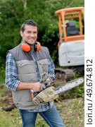 Man holding chainsaw, wearing ear protectors. Стоковое фото, агентство Ingram Publishing / Фотобанк Лори