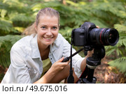 female photographer crouching among ferns. Стоковое фото, агентство Ingram Publishing / Фотобанк Лори