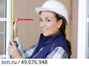 a happy woman measuring window frame. Стоковое фото, агентство Ingram Publishing / Фотобанк Лори