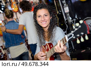Woman strumming guitar in music shop. Стоковое фото, агентство Ingram Publishing / Фотобанк Лори