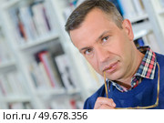 Portrait of man with arm of spectacles in his mouth. Стоковое фото, агентство Ingram Publishing / Фотобанк Лори