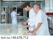young man learns to bake cakes with porfessionalnym baker. Стоковое фото, агентство Ingram Publishing / Фотобанк Лори