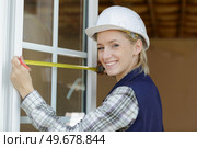 young woman measuring window with tape measurer. Стоковое фото, агентство Ingram Publishing / Фотобанк Лори