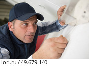 man fixing illuminated exit sign to wall. Стоковое фото, агентство Ingram Publishing / Фотобанк Лори
