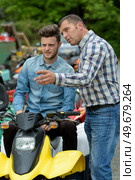 man giving instructions to young man sat on a quad. Стоковое фото, агентство Ingram Publishing / Фотобанк Лори
