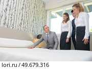 Man teaching hotel staff how to make bed. Стоковое фото, агентство Ingram Publishing / Фотобанк Лори