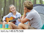 woman singing to boyfriend in a camp site. Стоковое фото, агентство Ingram Publishing / Фотобанк Лори