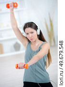 young beautiful woman in basement gym lifting weights. Стоковое фото, агентство Ingram Publishing / Фотобанк Лори
