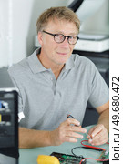 man repairing a computer using a multimeter. Стоковое фото, агентство Ingram Publishing / Фотобанк Лори