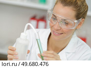 positive minded woman smiling while looking at a test tube. Стоковое фото, агентство Ingram Publishing / Фотобанк Лори