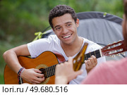 happy man playing guitar outside tent. Стоковое фото, агентство Ingram Publishing / Фотобанк Лори