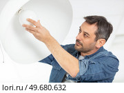 man changing light bulb in pendant lamp indoors. Стоковое фото, агентство Ingram Publishing / Фотобанк Лори