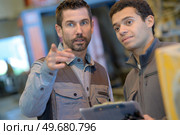 Man with clipboard giving instructions to younger colleague. Стоковое фото, агентство Ingram Publishing / Фотобанк Лори